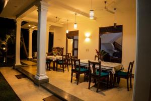 a dining room with a table and chairs on a porch at New Mangosteen Garden Villa in Hikkaduwa