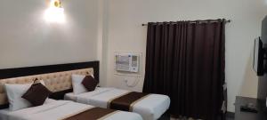 Habitación de hotel con 2 camas y ventana en J P PALACE, en Kushinagar