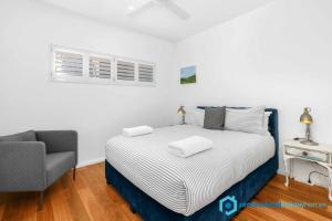 a bedroom with a bed and a chair in it at Ocean Dunes - Absolute Beachfront with Fireplace in Culburra Beach