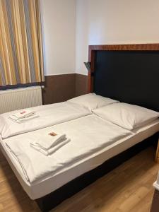 a bed with a black head board and white sheets at Hotel Castellana in Lessien