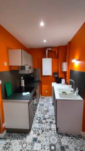 - une cuisine avec des murs orange et un évier blanc dans l'établissement Appartement de Louise et Adrien, à Gray
