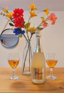 una bottiglia di vino e due bicchieri su un tavolo con fiori di Fe Wo Auf der Alb 