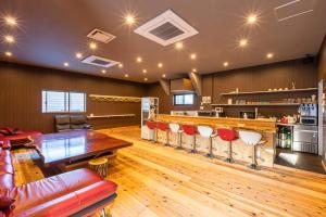 een grote kamer met een bar met rode stoelen bij ヴィラかくれが in Sano