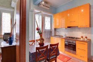 ローマにあるOlimpia Apartmentのキッチン(オレンジ色のキャビネット、テーブル、椅子付)