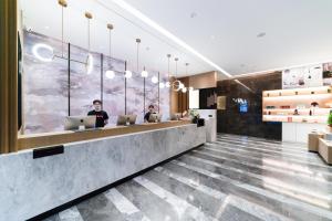 a lobby with two people sitting at a counter with laptops at Atour Hotel Hangzhou Binjiang Powerlong City in Hangzhou