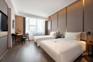 a hotel room with two beds and a desk at Atour Hotel Dalian Xinghai Square in Dalian
