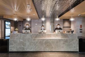 three people wearing face masks in a lobby with their laptops at Atour Hotel Fuzhou Wusi Road Hot Spring Park in Fuzhou