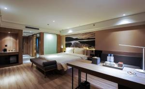 ハルビン市にあるAtour Hotel Harbin Haxi High Speed Railway Stationのベッド、デスク、デスクが備わるホテルルームです。