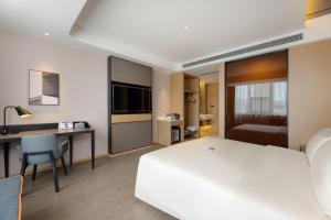 a hotel room with a white bed and a desk at Atour Hotel Dalian Xinghai Square in Dalian