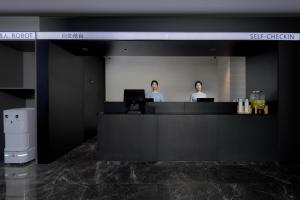 two people standing at a counter in an office at Atour Light Hotel Changsha IFC Huangxing Road Pedestrian Street in Changsha