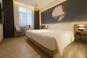 - une chambre avec un grand lit blanc et un miroir dans l'établissement Atour Light Hotel Beijing Jianguomen CBD, à Pékin