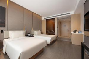 a hotel room with two beds and a couch at Atour Hotel Dalian Xinghai Square in Dalian