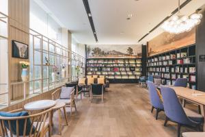 une bibliothèque avec des tables, des chaises et des étagères dans l'établissement Atour Music Hotel Hangzhou West Lake, à Hangzhou