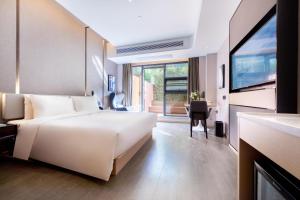 a bedroom with a large white bed and a television at Atour Hotel Zhuhai High Tech Zone University Town Government Affairs Center in Zhuhai