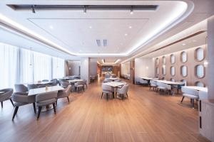 um restaurante com mesas e cadeiras num quarto em Atour Hotel Qingdao Laoshan Shilaoren Beach em Qingdao