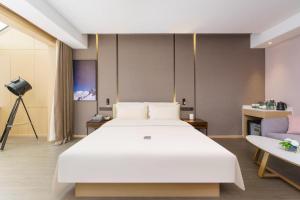 a bedroom with a large white bed and a couch at Atour Hotel Dalian Xinghai Square in Dalian