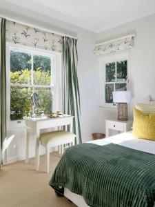 um quarto com uma cama, uma secretária e 2 janelas em La Belle Vie em Franschhoek