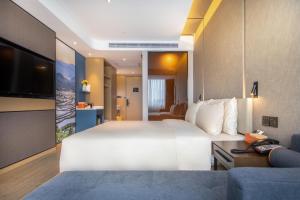 a hotel room with a large white bed and a couch at Atour Hotel Kunming Cuihu in Kunming