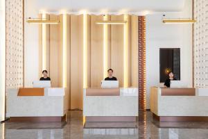 two people sitting at desks in a lobby with their laptops at Atour Hotel Xiamen Gaoqi Airport Chenggong Avenue in Xiamen