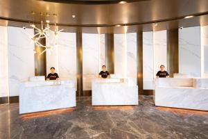 tres hombres sentados en los escritorios de recepción en el vestíbulo en Atour Hotel Zhaoqing Qixingyan, en Zhaoqing