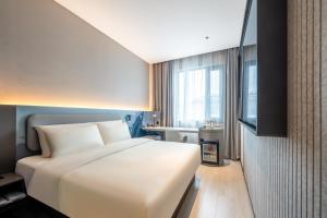a bedroom with a large white bed and a window at Atour Light Hotel Guangzhou Panyu Hanxi Changlong in Guangzhou