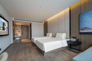 a bedroom with a white bed and a flat screen tv at Atour Hotel Anji Longshan in Anji