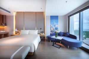a bedroom with a large white bed and a blue couch at Atour S Hotel Zhuhai Gongbei Port NetEase Selected in Zhuhai
