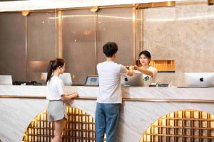 a man and two women standing in front of a counter at Atour Hotel Chongqing Guanyinqiao Flower Garden in Chongqing