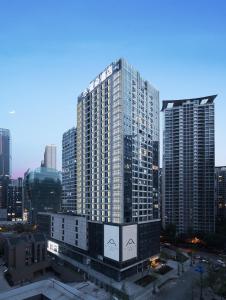 Atour Hotel Chengdu Jiuyanqiao NetEase Selected في تشنغدو: مبنى طويل أمام أفق المدينة