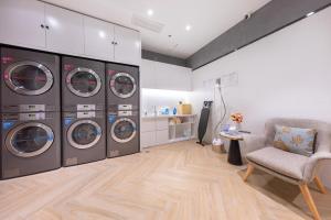 a laundry room with four washing machines and a chair at Atour Hotel Yichun Administrative Center in Yichun