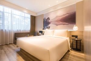 um quarto com uma grande cama branca e uma grande janela em Atour Hotel Guangzhou Huadu Square em Huadu