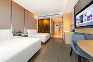 a hotel room with two beds and a flat screen tv at Atour Hotel Urumqi Airport Degang Wanda in Ürümqi
