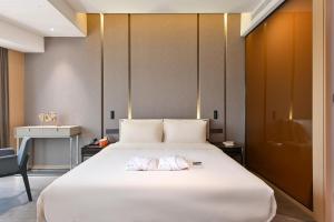 Cette chambre comprend un grand lit blanc et une chaise. dans l'établissement Atour Hotel Tianjin Eye, à Tianjin