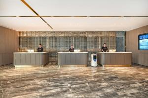 a rendering of a lobby with three people at counters at Atour Hotel Tianjin Eye in Tianjin