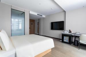 a bedroom with a white bed and a fireplace at Atour X Hotel Zhuhai Gongbei Port High Speed Railway Station in Zhuhai