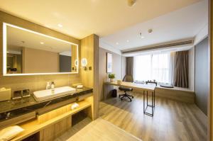 a bathroom with a sink and a mirror and a desk at Atour Hotel Shenyang Olympic Yingpan Street in Shenyang