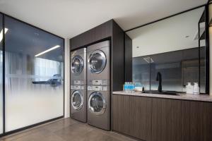 a laundry room with three washers and a counter at Atour Hotel Nantong North Street Vientiane City in Nantong