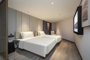 ein Hotelzimmer mit 2 Betten und einem Flachbild-TV in der Unterkunft Atour Hotel Nanchang Bayi Square Provincial Television Station in Nanchang
