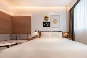 a bedroom with a large white bed and a couch at Atour Hotel Shenzhen Nanshan Vanke Yuncheng in Shenzhen