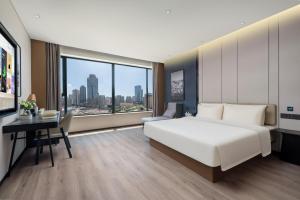 Huangdao的住宿－青岛唐岛湾井冈山地铁站亚朵酒店，卧室配有一张白色大床和一张书桌