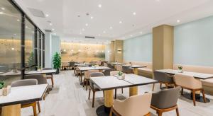a restaurant with tables and chairs in a room at Atour Hotel Xuzhou East Jianguo Road Suning Plaza in Xuzhou