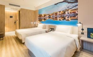 two beds in a hotel room with a painting on the wall at Atour Hotel Wuxi Sanyang Plaza in Wuxi