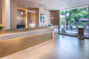 a lobby with two people standing at a reception desk at Atour X Hotel Shanghai Jinshan Wanda Plaza City Beach in Jinshan