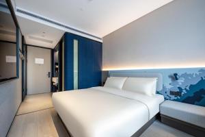a bedroom with a white bed and a blue wall at Atour Light Hotel Guangzhou Panyu Hanxi Changlong in Guangzhou