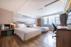 a hotel room with two beds and a desk at Atour Hotel Zhongshan Er Road Lihe Plaza in Zhongshan