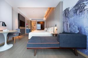 a hotel room with a bed and a couch at Atour Hotel Shenzhen Fuhai International Convention and Exhibition Center in Bao'an