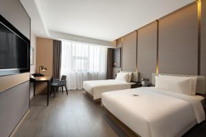 Cette chambre comprend deux lits et une télévision. dans l'établissement Atour S Hotel Xinghai Square, à Dalian