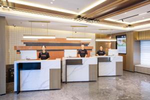 3 Personen sitzen an einem Schreibtisch mit Laptops in der Unterkunft Atour Hotel Beijing Capital Airport New International Exhibition Center in Peking