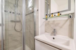 a white bathroom with a sink and a shower at Pauline's Home Gambetta in Reims