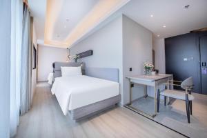 a bedroom with a bed and a table and a desk at Atour Light Hotel Shenzhen Nanshan Nanyouxi Station in Shenzhen